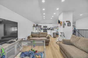 Living room featuring light wood finished floors, recessed lighting, and lofted ceiling