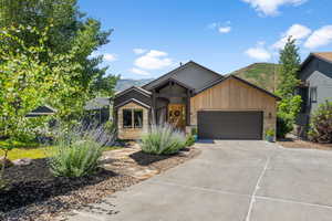 View of front of home featuring driveway, an attached garage, a mountain view, and stone siding
