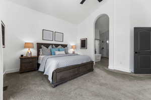 Bedroom with arched walkways, carpet, ensuite bath, lofted ceiling, and a ceiling fan