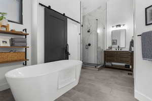 Full bathroom featuring a marble finish shower, vanity, and a soaking tub