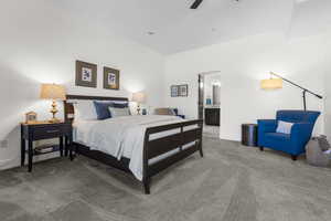 Carpeted bedroom featuring ensuite bath and ceiling fan