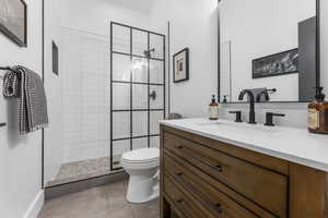 Full bath featuring vanity, tiled shower, and tile patterned flooring