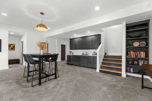 Dining space featuring wine cooler, wet bar, light carpet, recessed lighting, and stairs