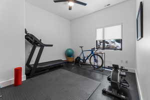 Exercise room with a ceiling fan and baseboards
