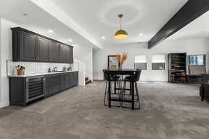 Dining room with beverage cooler, bar with sink, carpet, stairs, and recessed lighting