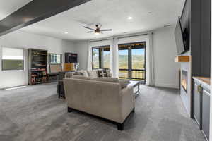 Carpeted living area with a fireplace, a textured ceiling, a ceiling fan, and recessed lighting