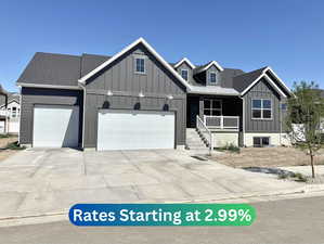 View of front facade featuring board and batten siding, a porch, a garage, driveway, and a standing seam roof