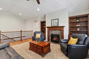 Living room with a ceiling fan, arched walkways, vaulted ceiling, recessed lighting, and a fireplace