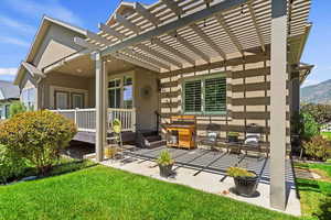 Back of house with a pergola, stucco siding, a lawn, and a patio