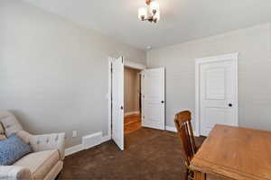 Office space featuring dark colored carpet and baseboards