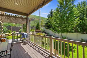 Wooden deck with a fenced backyard, a pergola, and a mountain view