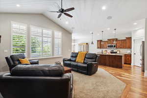 Living room featuring ceiling fan, light wood-type flooring, recessed lighting, lofted ceiling, and a chandelier