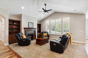 Living area with a tiled fireplace, ceiling fan, light wood-style floors, recessed lighting, and vaulted ceiling
