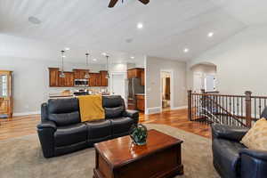 Living area featuring a ceiling fan, light wood finished floors, arched walkways, recessed lighting, and lofted ceiling
