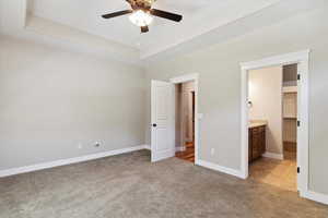 Unfurnished bedroom with light colored carpet, connected bathroom, and ceiling fan