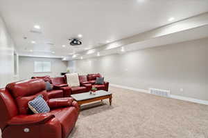 Carpeted home theater room with recessed lighting and bar