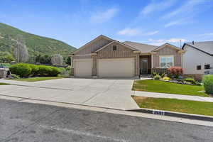 View of front of home with board and batten siding, a garage, brick siding, a mountain view, and driveway