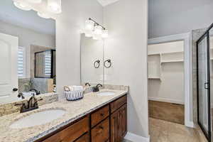 Full bath featuring a shower stall, a walk in closet, double vanity, and tile patterned flooring