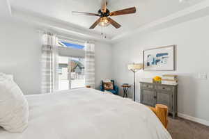 Bedroom with a tray ceiling, carpet, and ceiling fan