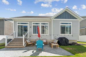 Back of property with board and batten siding, a patio area, and entry steps