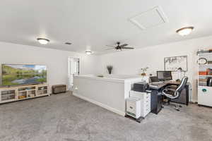 Carpeted office space with attic access and a ceiling fan
