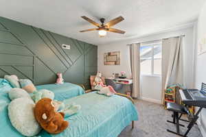 Bedroom with carpet, a ceiling fan, and a textured ceiling