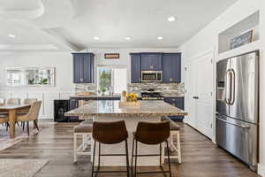 Kitchen featuring stainless steel appliances, blue cabinetry, a breakfast bar area, backsplash, and a textured ceiling