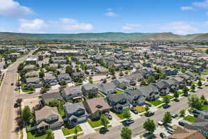 Aerial view of property and surrounding area featuring mountains and nearby suburban area
