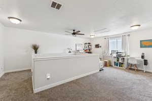 Carpeted home office featuring a textured ceiling and a ceiling fan