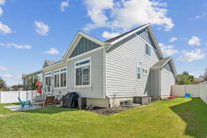 Rear view of property with board and batten siding, a fenced backyard, and a patio area