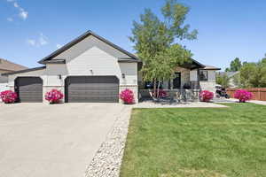 View of front of house with an attached garage, driveway, and stone siding
