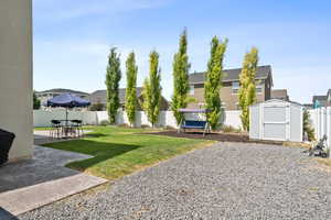 Fenced backyard featuring a patio, a shed, and a residential view