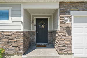 Doorway to property with stone siding and a garage