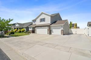 View of front of house with a gate, driveway, stone siding, and a garage
