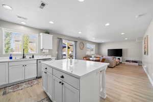 Kitchen featuring stainless steel dishwasher, light wood-style flooring, a kitchen island, recessed lighting, and white cabinetry