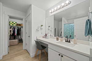 Full bathroom with wood finished floors, vanity, a spacious closet, and a shower with shower curtain