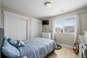 Bedroom with light wood finished floors and two closets