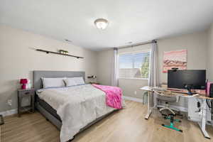 Bedroom with light wood-type flooring and an office area