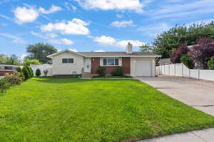 Ranch-style home with driveway, an attached garage, a chimney, and brick siding