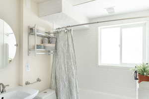 Bathroom with a sink and shower / bath combination with curtain