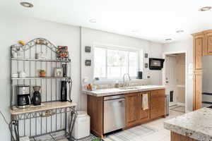 Kitchen featuring appliances with stainless steel finishes, light granite countertops, light tile patterned floors, wood cabinets, and recessed lighting