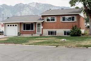 Tri-level home featuring an attached garage, brick siding, and a mountain view