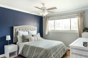Bedroom featuring ornamental molding, dark hardwood flooring, and a ceiling fan