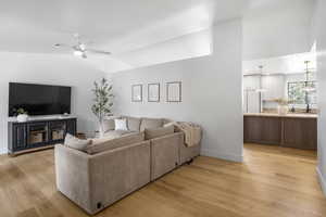 Living room featuring light wood finished floors, a ceiling fan, and vaulted ceiling