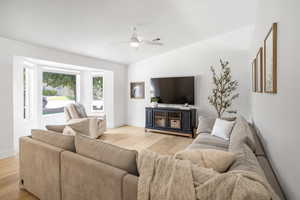 Living room with light wood finished floors, vaulted ceiling, and a ceiling fan