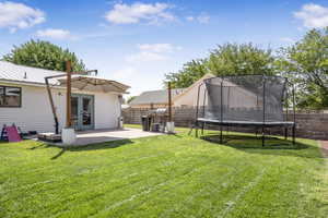 Fenced backyard with french doors, a trampoline, and a patio