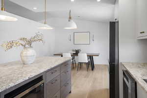 Kitchen with vaulted ceiling, light wood-type flooring, freestanding refrigerator, recessed lighting, and decorative light fixtures