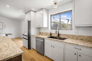 Kitchen featuring stainless steel appliances, light wood-style flooring, white cabinetry, and recessed lighting