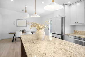 Kitchen with freestanding refrigerator, light wood-style flooring, recessed lighting, pendant lighting, and dishwasher