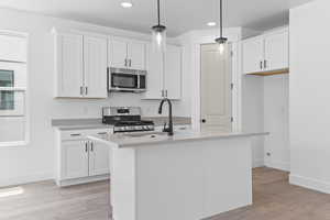 Kitchen featuring appliances with stainless steel finishes, light wood finished floors, recessed lighting, light countertops, and white cabinets